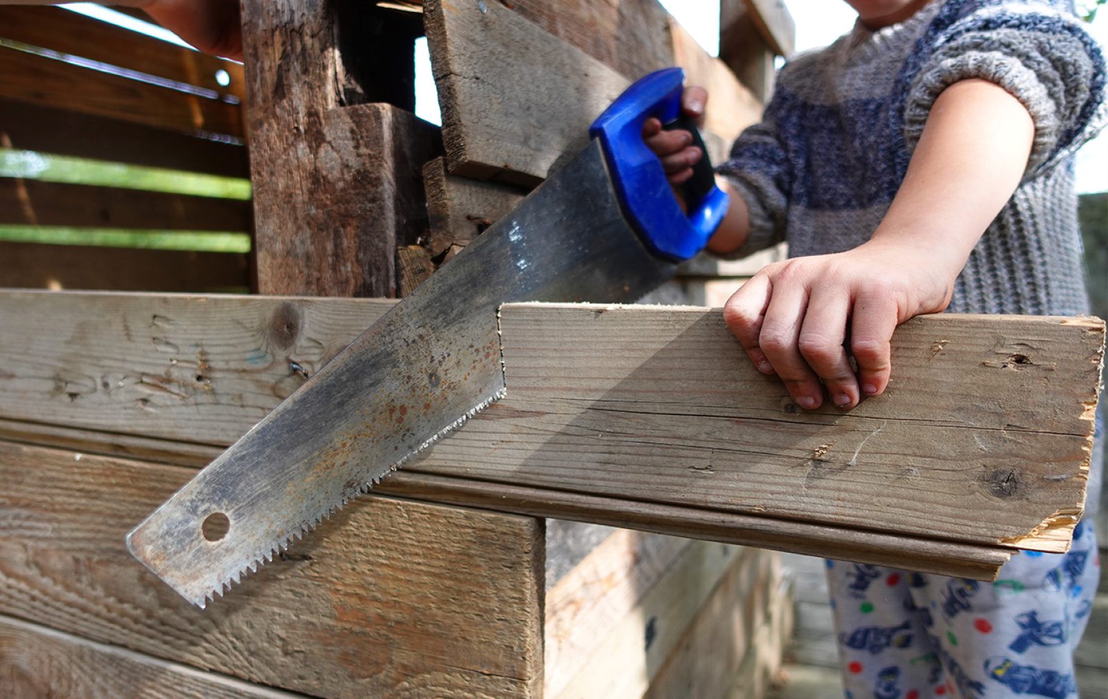 Kinderhände sägen eine Holzplatte